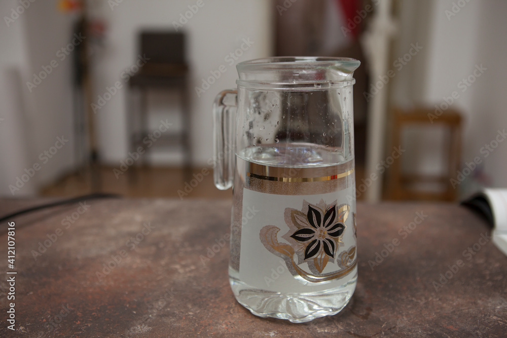 Glass jug with water on the table in the living room. Glass jug with water on the table in the living room.