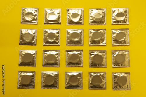 Flat lay with blank condoms on yellow background