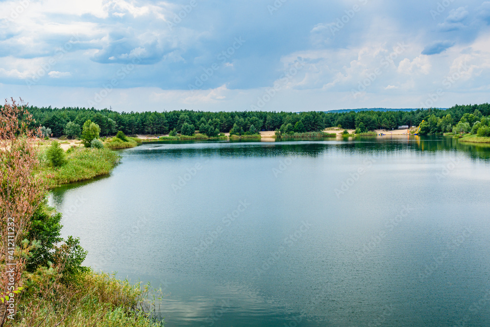 View on a lake in the abandoned sand quarry and dramatic sky