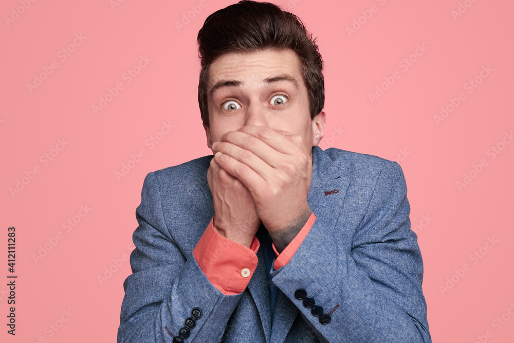 Shocked young man covering mouth Shocked young man covering mouth