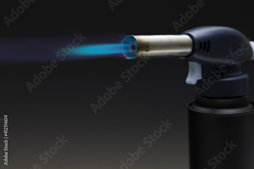 Blue flame from a gas torch burner on black background photo
