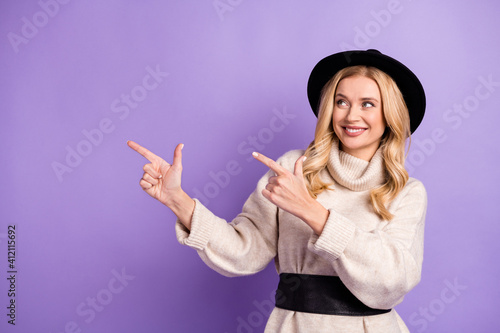 Photo of optimistic blond lady point look empty space wear cap sweater isolated on lilac color background