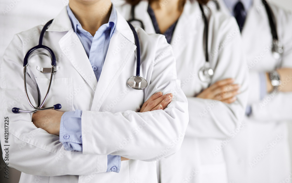 Group of modern doctors standing as a team with arms crossed in hospital office and ready to help patients. Medical help, insurance in health care, best disease treatment and medicine concept Group of modern doctors standing as a team with arms crossed in hospital office and ready to help patients. Medical help, insurance in health care, best disease treatment and medicine concept