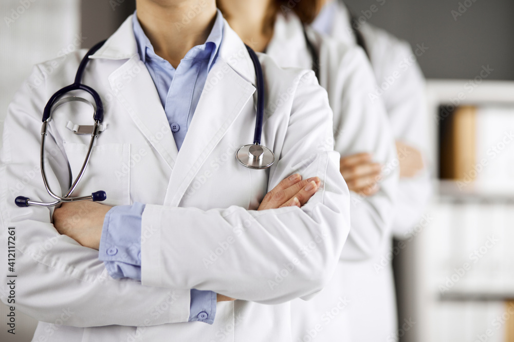 Group of modern doctors standing as a team with arms crossed in hospital office and ready to help patients. Medical help, insurance in health care, best disease treatment and medicine concept Group of modern doctors standing as a team with arms crossed in hospital office and ready to help patients. Medical help, insurance in health care, best disease treatment and medicine concept