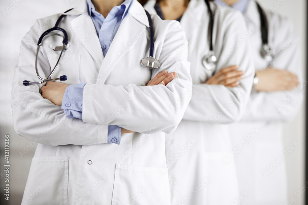 Group of modern doctors standing as a team with arms crossed in hospital office and ready to help patients. Medical help, insurance in health care, best disease treatment and medicine concept Group of modern doctors standing as a team with arms crossed in hospital office and ready to help patients. Medical help, insurance in health care, best disease treatment and medicine concept