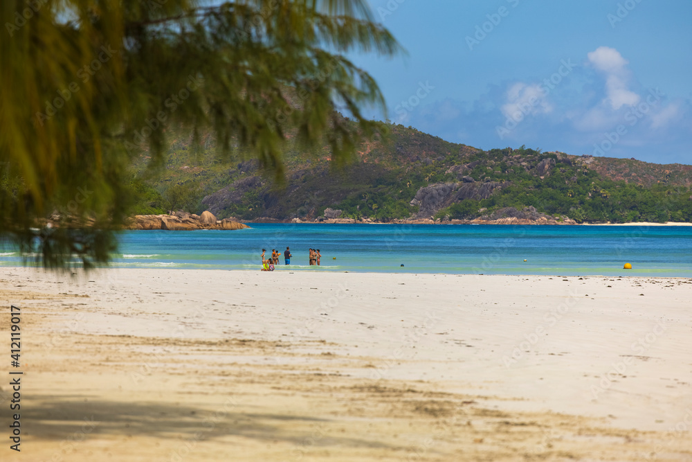 Small group of tourists on Cote Do'r Beach along the northern tip coast of Praslin island