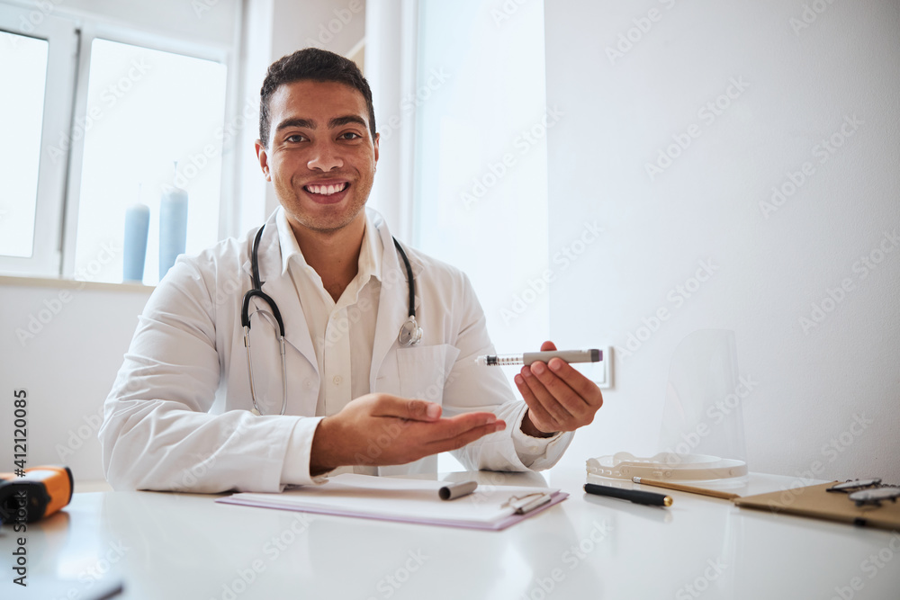 Positive strong minded therapist in white robe with stethoscope working in the cabinet Positive strong minded therapist in white robe with stethoscope working in the cabinet