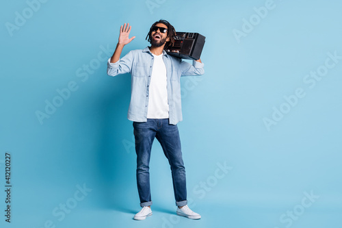 Full length body size view of nice cheerful guy carrying player dancing having fun isolated over bright blue color background