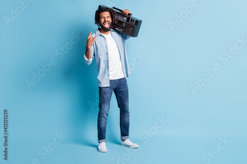 Full length body size view of nice crazy cheerful guy carrying player showing horn sign isolated over bright blue color background