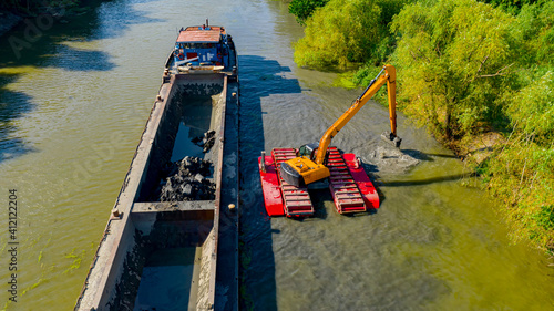 Quadro em tela Aerial view of river, canal is being dredged by excavator