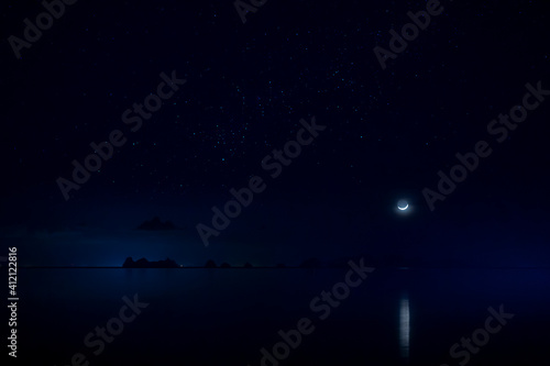 Fototapeta Naklejka Na Ścianę i Meble -  The sky with star and moon is above on mountain at the lake in blue night.