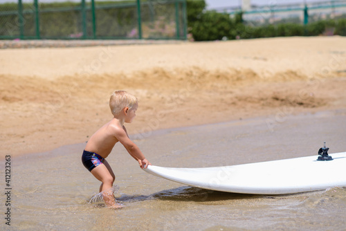 happy little baby with surf board on the seaside in summer