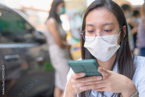 Checking the social media feed. Portrait of young woman on the street food wearing face protective mask to prevent Coronavirus and anti-smog and using smartphone
