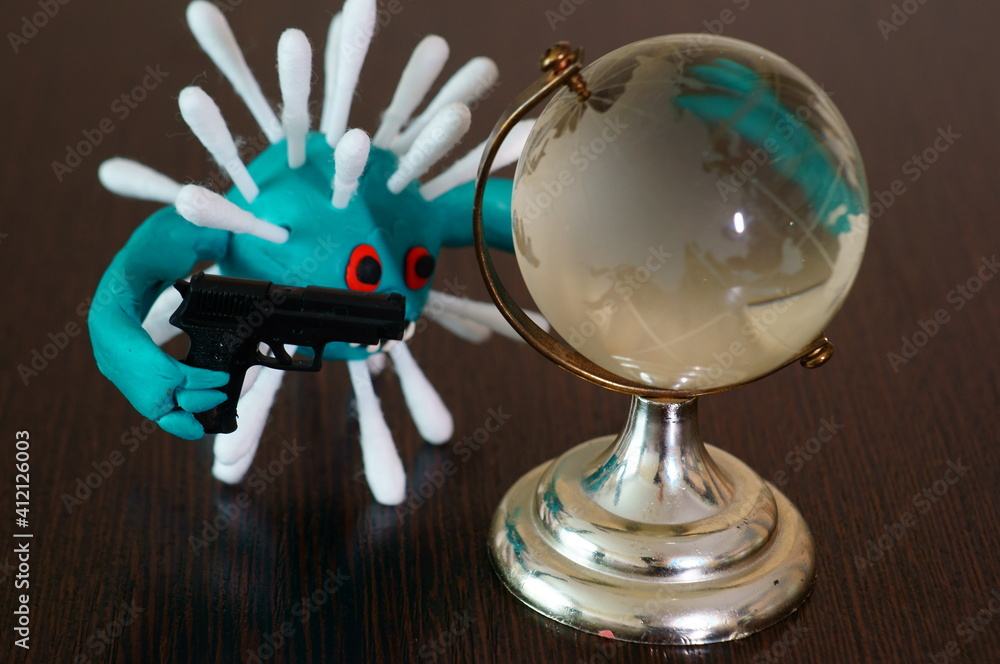 The figure of the virus with a toy gun. Next to it is a small glass globe. The figure of the virus with a toy gun. Next to it is a small glass globe.