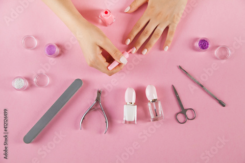 Manicure accessories on an isolated pink background. Woman hands.