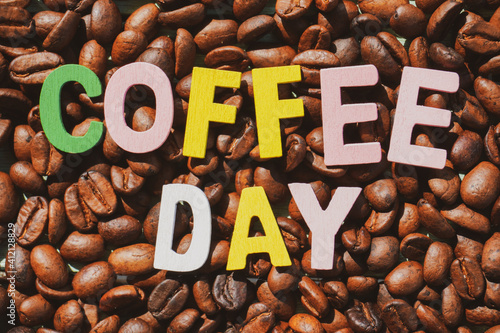 Coffee Day alphabets on the roasted coffee beans background.