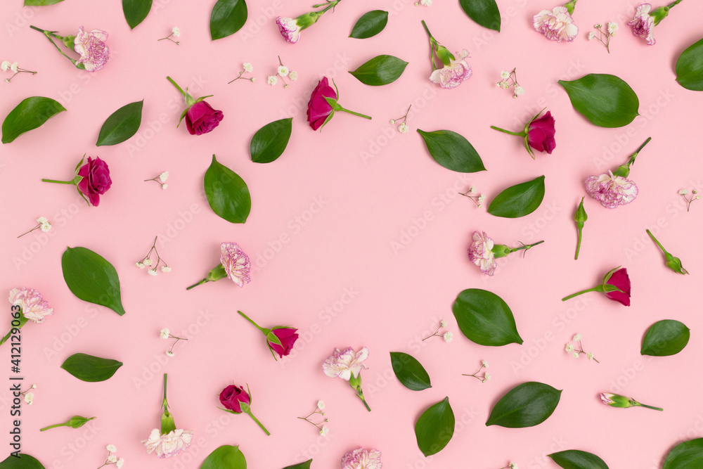 Pattern made of flowers and green leaves on a pink background with copy space. Greeting card concept. Pattern made of flowers and green leaves on a pink background with copy space. Greeting card concept.