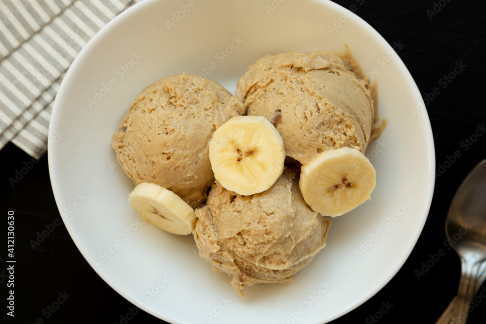 Homemade Peanut Butter Banana Ice Cream in a Bowl on a black surface, top view. Flat lay, overhead, from above. Close-up. Homemade Peanut Butter Banana Ice Cream in a Bowl on a black surface, top view. Flat lay, overhead, from above. Close-up.