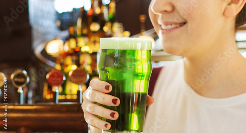 alcohol drinks and st patrick's day concept - close up of woman with green beer in glass over bar background