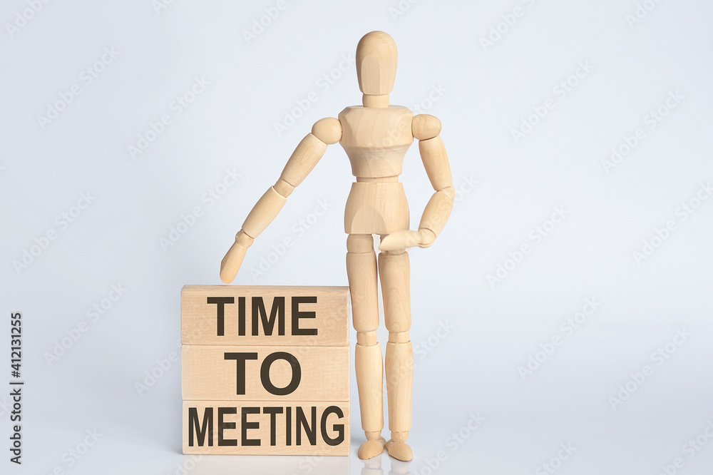 Wooden man shows with a hand text TIME TO MEETING concept on the wooden block Wooden man shows with a hand text TIME TO MEETING concept on the wooden block