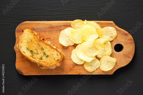 Homemade French Onion Melt Cheese Sandwich with Chips on a rustic wooden board on a black background, top view. Flat lay, overhead, from above. Copy space.