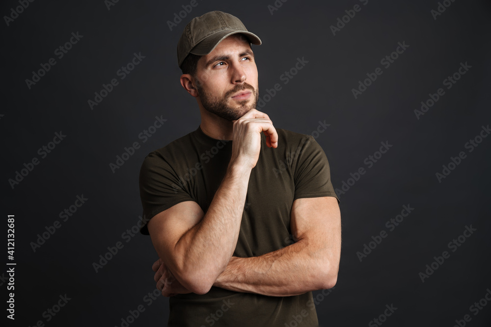 Focused masculine military man posing and looking aside Focused masculine military man posing and looking aside