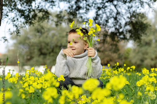 The boy collects flowers in a yellow field. Image with toning. Focus on the boy. Blurred flowers © Алина Битта