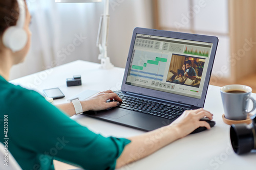 technology  post production and vlog concept - close up of woman in headphones working with video editor program on laptop computer at home office