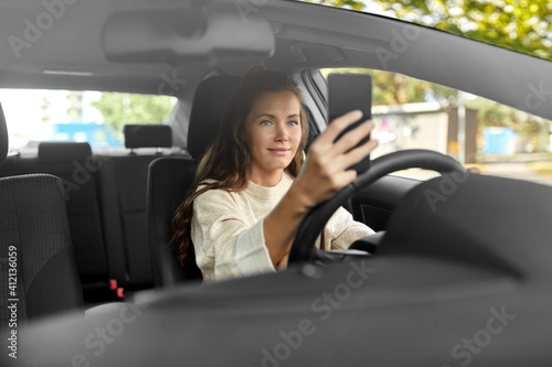 safety and people concept - happy smiling young woman or female driver driving car and taking selfie with smartphone © Syda Productions