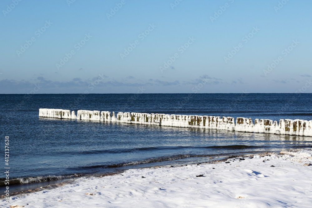 beach at winter with breakwater in ice