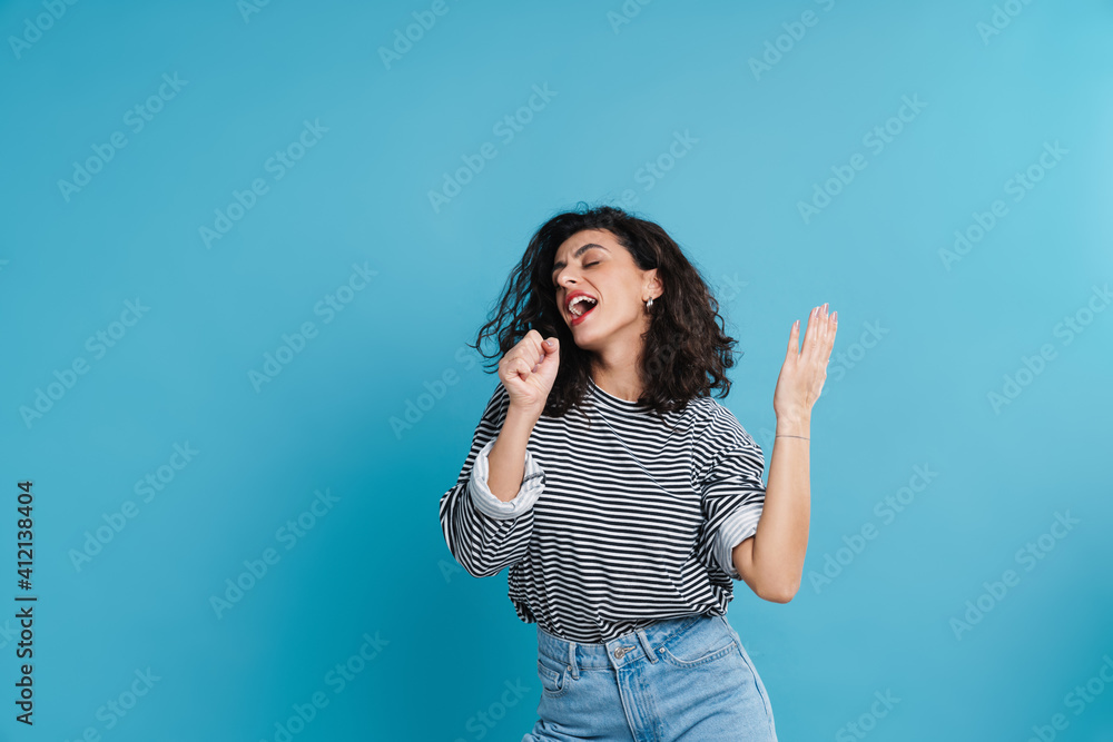 Fototapeta premium Joyful beautiful girl singing and dancing at camera