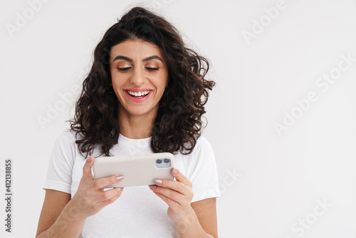 Joyful brunette girl smiling and using mobile phone