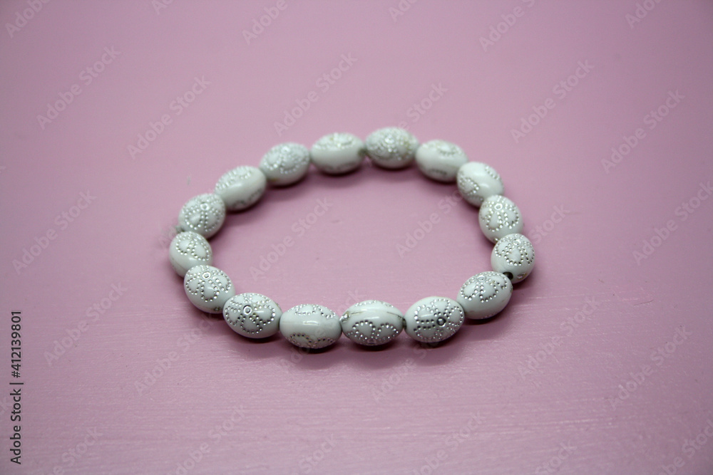 A bracelet made of beads on a pink background. A bracelet made of beads on a pink background.