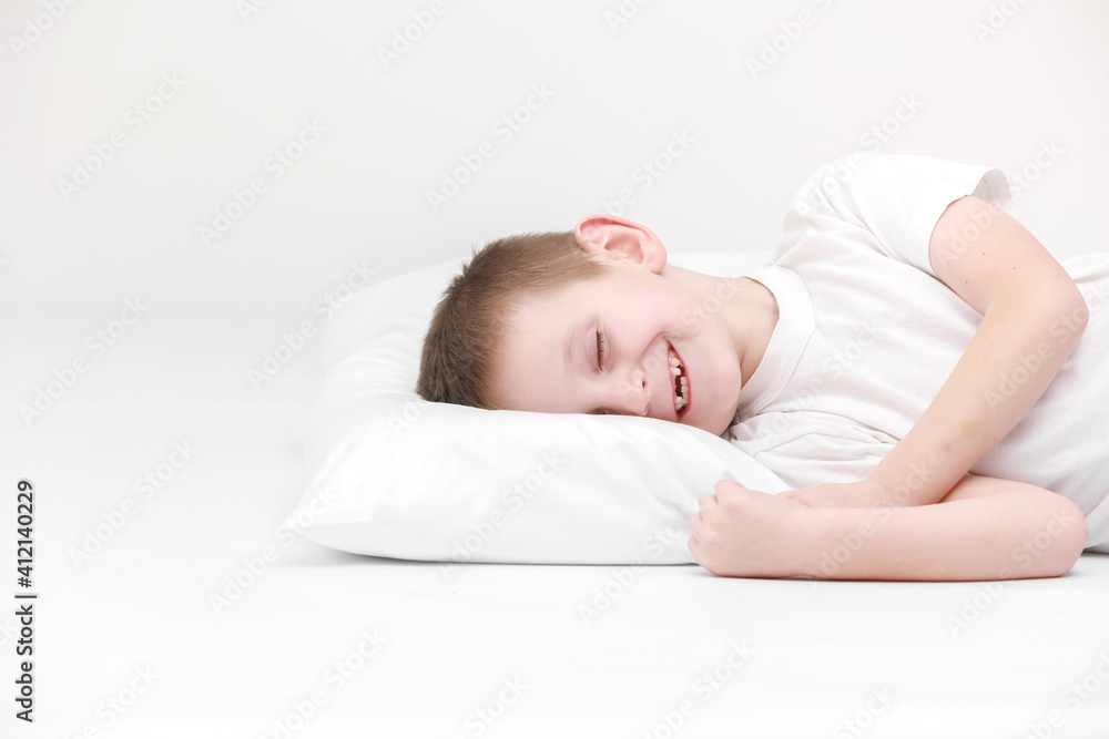 portrait of a happy cute little boy waking up in the morning and lying on a white pillow isolated on a white background. fresh and cozy bedding sheets. Bedtime for kids. concept of happy dreaming portrait of a happy cute little boy waking up in the morning and lying on a white pillow isolated on a white background. fresh and cozy bedding sheets. Bedtime for kids. concept of happy dreaming
