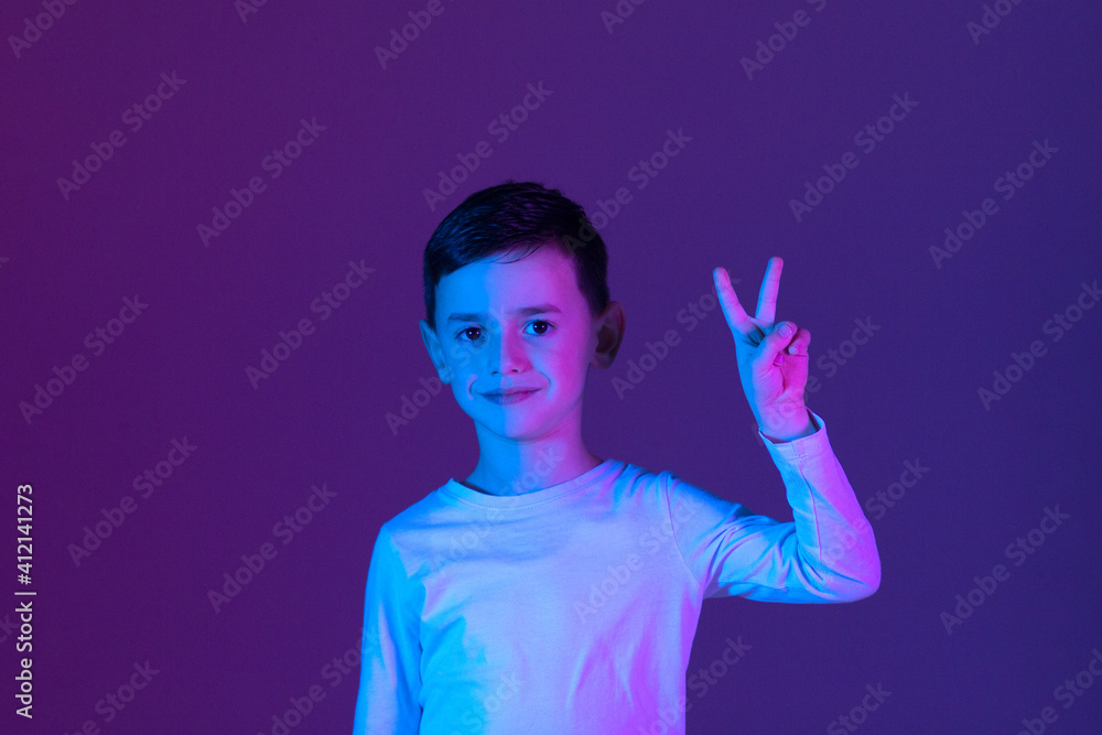 a child making the victory gesture with his hand illuminated with neon lights. Winning concept a child making the victory gesture with his hand illuminated with neon lights. Winning concept