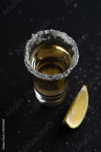 Gold Mexican Tequila shot with lime slice and salt.