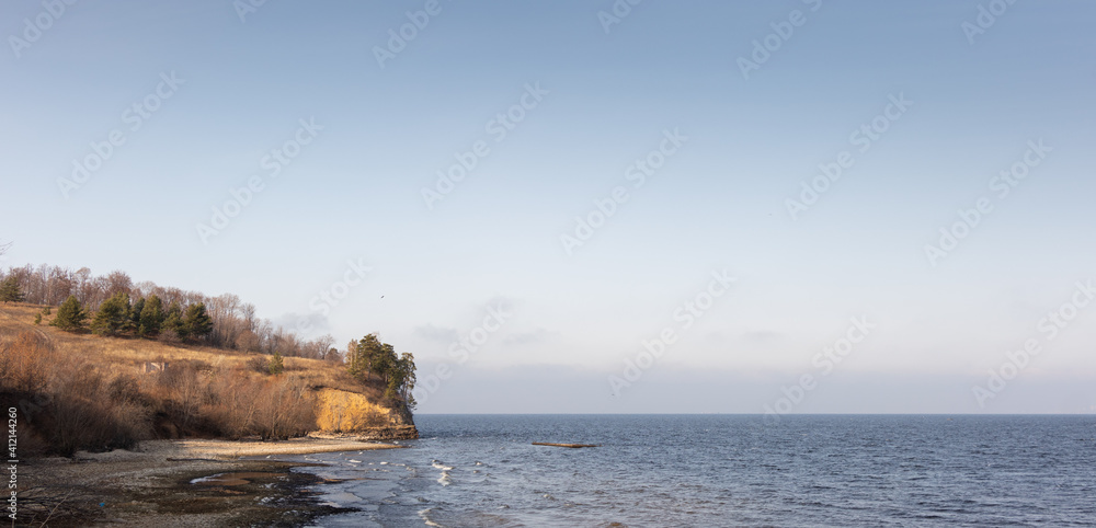 Sea landscape with rocky coast and trees with yellow leaves