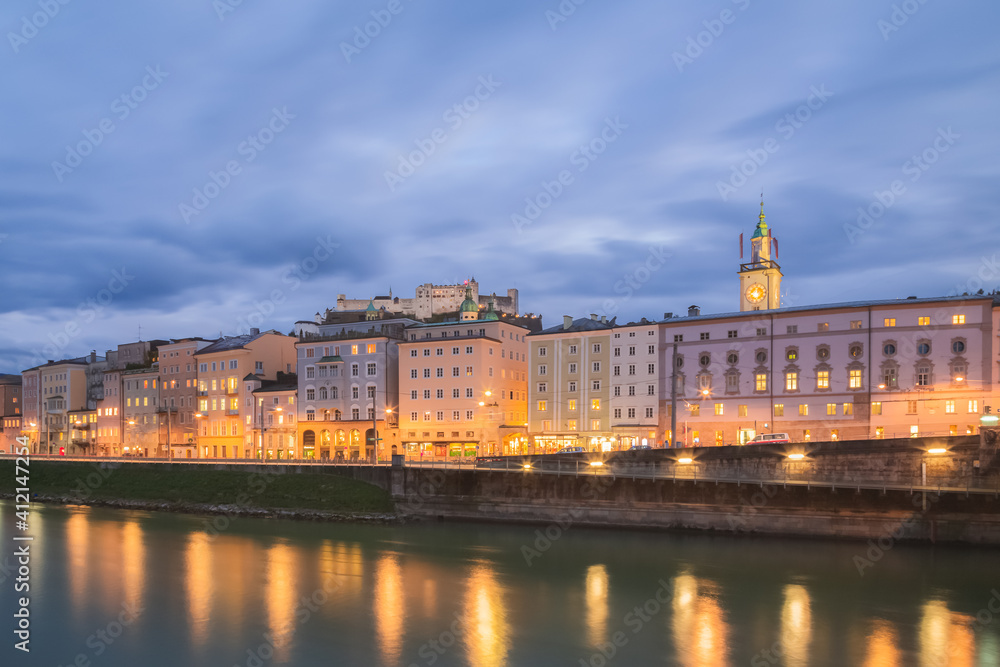Old town cityscape view at night along the Salzach River in Salzburg, Austria and the hilltop Fortress Hohensalzburg.
