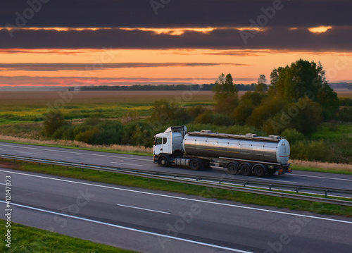 Isothermal Tank truck driving on highway. Oil and Gas Transportation and Logistics. Metal chrome cistern tanker with petrochemicals products. Liquid Chemical Freight photo