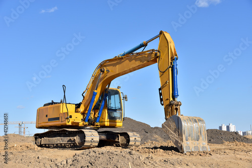 Excavator on earthworks at construction site. Backhoe on foundation work and road construction. Heavy machinery and construction equipment