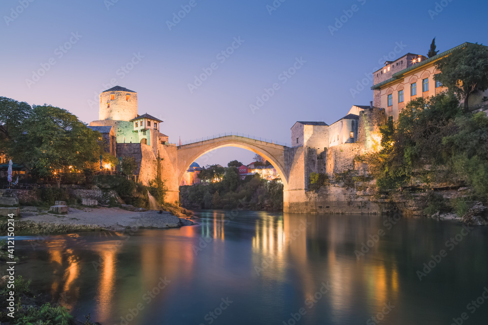 Night cityscape view of the iconic illuminated Stari Most bridge, Neretva River and old town of Mostar, Bosnia and Herzegovina.