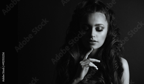 Young sad woman with naked shoulders posing in the dark
