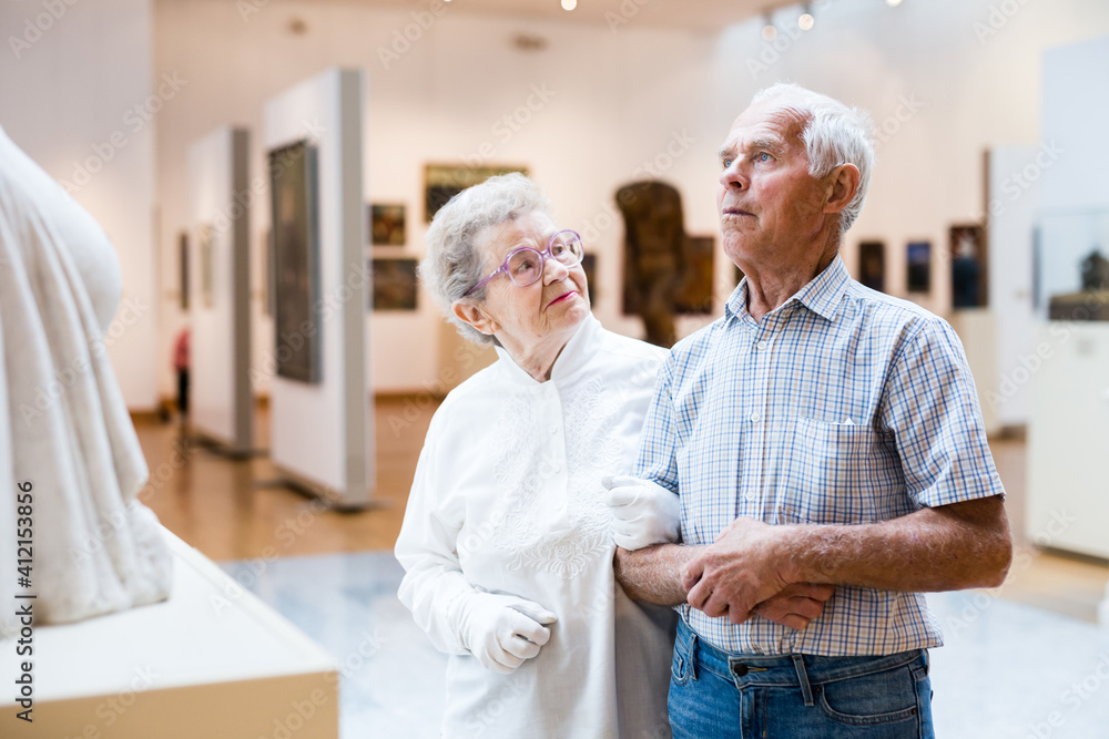 Obraz premium mature European couple examines paintings in an exhibition in hall of art museum