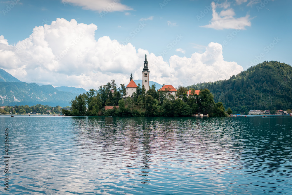 St Martin church on island and Bled lake landscape with mountain. Summer cloud day. Slovenia