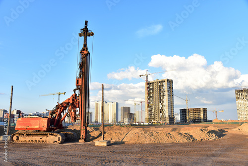 Vibrating hydraulic hammer. Hydraulically driven free-fall hammer. Piling methods for deep foundation. Tower cranes in action at construction site. Crane the build the high-rise building.
