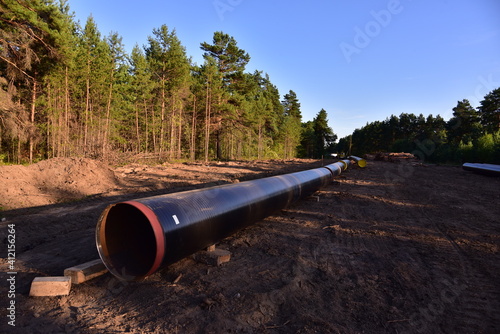 Natural gas pipeline construction work in forest area. Petrochemical Pipe on top of wooden supports. Installation and Construction the Pipeline for transport gas to LNG plant