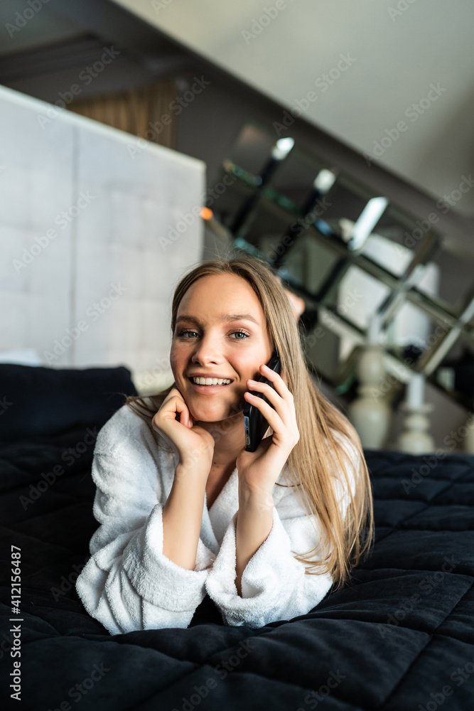 Young woman resting in bed talking on the phone Young woman resting in bed talking on the phone