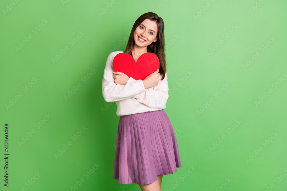Photo of young pretty attractive beautiful happy positive smiling girl embrace red heart isolated on green color background Photo of young pretty attractive beautiful happy positive smiling girl embrace red heart isolated on green color background