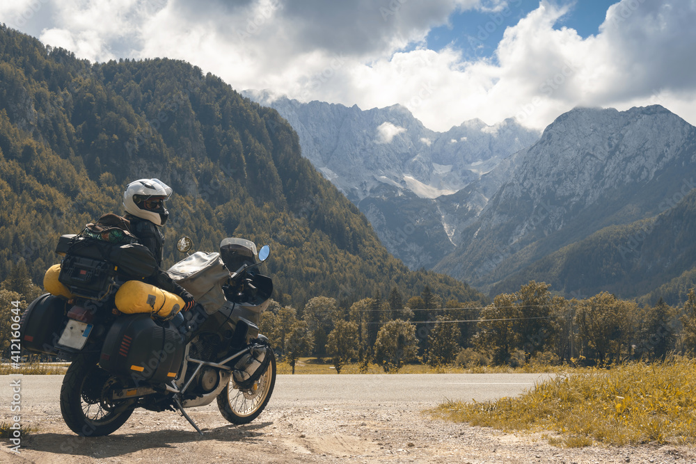 Girl in full body protection, hermetic packing bag. Water resistant, tourer motorcycle for traveling. Copy space, on a background of autumn mountains, travel and freedom. Zgornje Jezersko Slovenia Girl in full body protection, hermetic packing bag. Water resistant, tourer motorcycle for traveling. Copy space, on a background of autumn mountains, travel and freedom. Zgornje Jezersko Slovenia