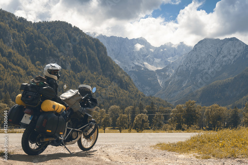 Girl in full body protection, hermetic packing bag. Water resistant, tourer motorcycle for traveling. Copy space, on a background of autumn mountains, travel and freedom. Zgornje Jezersko Slovenia